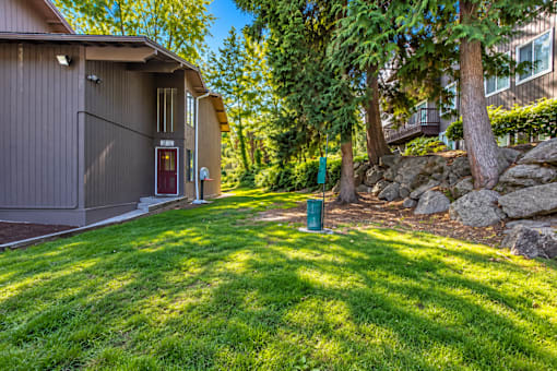 A house with a green trash can and a red door.