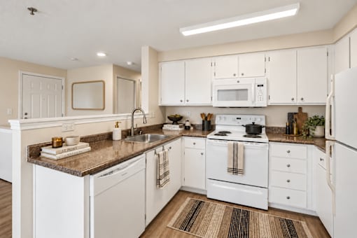 A kitchen with white appliances and cabinets.