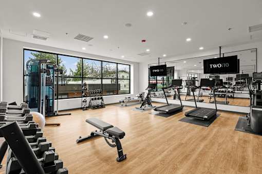 A gym with a variety of equipment including treadmills, weights, and exercise machines at Two 10 by Vintage, Shoreline