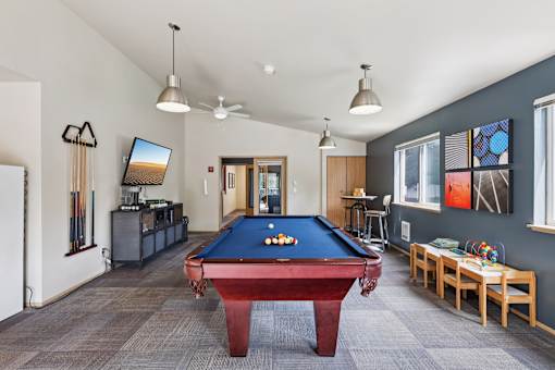 A room with a pool table and a television.