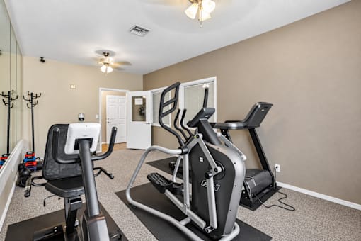 A home gym with a treadmill, elliptical trainer and a stationary bike.