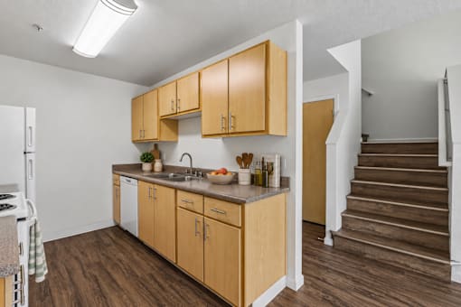 A kitchen with wooden cabinets and a countertop with a sink and a bowl of fruit on it.