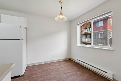 A room with a window and a white fridge.