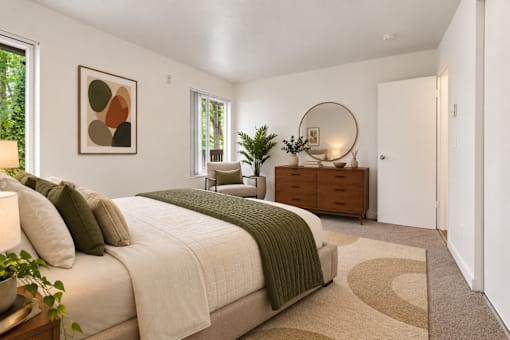 A bedroom with a large bed and a round mirror on the dresser.