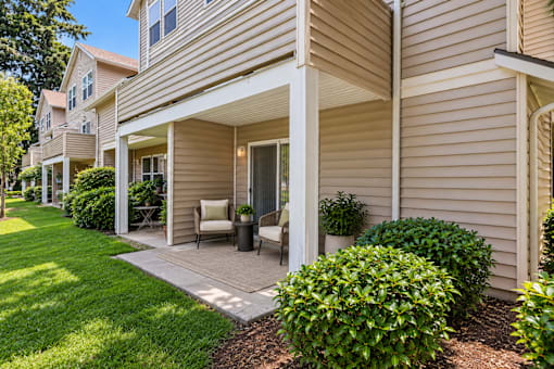 A beige house with a covered patio and a white chair.