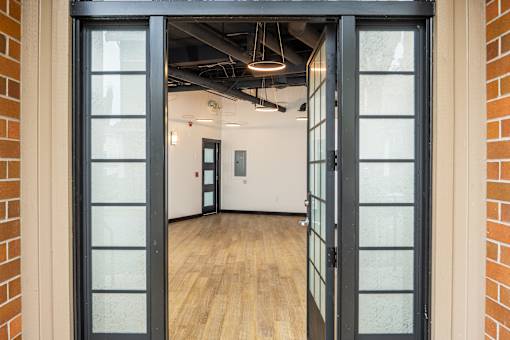 A glass doorway leads to a room with wooden flooring and white walls.at Fairview Village Homes, Fairview