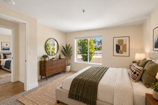 A bedroom with a large bed and a view of the outdoors through a window.