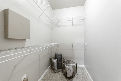the walk in closet in a large room with white walls and a shelf with baskets