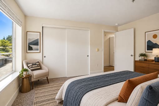 A bedroom with a bed, chair, and two pictures on the wall.