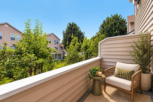A balcony with a chair and a table with a plant on it.