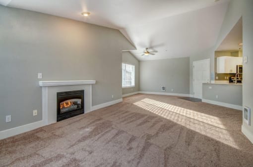 3 BR Apartments in Dupont WA - Clock Tower Village - Unfurnished Living Room With Plush Carpet, a Fireplace, and a Sliding Glass Door With Shutters