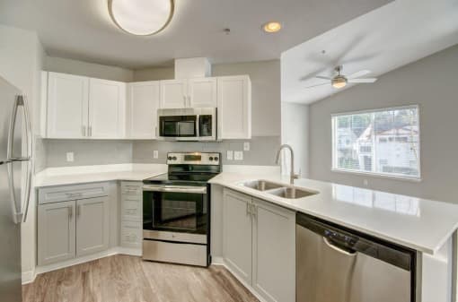 2 BR Apartments in Dupont WA - Clock Tower Village - Modern Kitchen With Stainless Steel Appliance Suite, Spacious White Cabinetry, and Sleek Counters