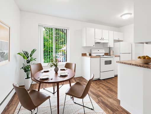 A dining room with a table set for four and chairs around it.