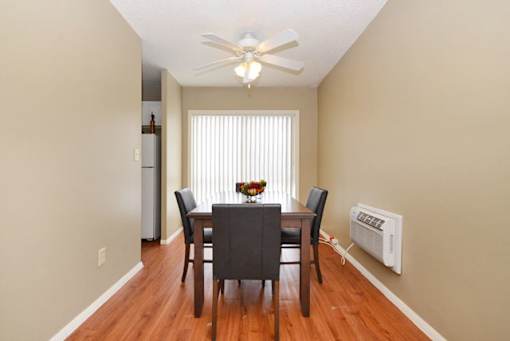 A dining room with a table and chairs and a ceiling fan.