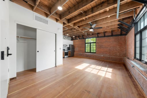 an open living room with exposed brick and wood ceilings and a large window