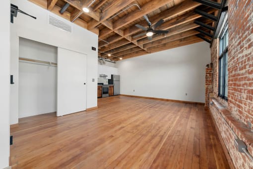 an empty living room with wood floors and a brick wall