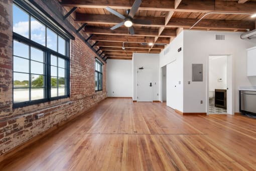 an empty room with wood floors and a brick wall and large windows
