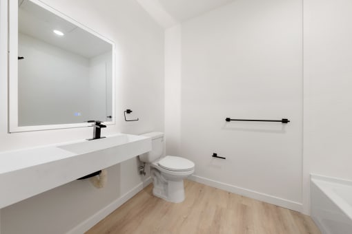 Apartments In Upper Land Park, Sacramento, CA For Rent - Market Club At The Mill - Full Bathroom With Shower, Wood-Style Flooring, White-topped Vanity, And Dark Wood Cabinetry