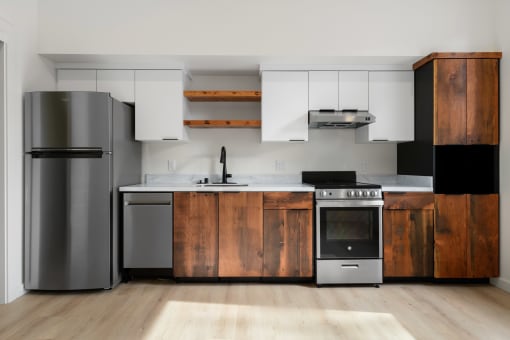 Upper Land Park Sacramento CA Apartments for Rent - Market Club at The Mill - Kitchen with Silver Appliances,Wood-Style and White Cabinetry, White Marble-Style Counter, Plank Flooring, and Black Hardware