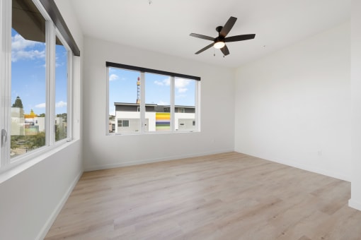 Studio Apartments in Upper Land Park Sacramento CA - Market Club at The Mill - Unfurnished Living Room Space with Large Windows, Plank-Style Flooring, and Ceiling Fan