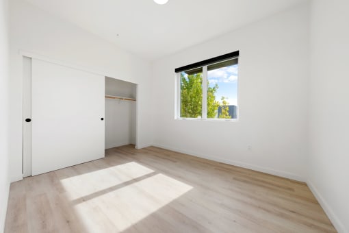 1 BR Apartments in Upper Land Park Sacramento CA - Market Club at The Mill - Unfurnished Bedroom Space with Light Plank-Style Flooring, Window, and Closet