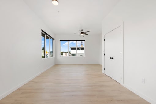 Pet-Friendly Apartments In Upper Land Park, Sacramento - Market Club At The Mill - Empty Living Room With Windows, Wood-Style Flooring, Closet, And Ceiling Fan