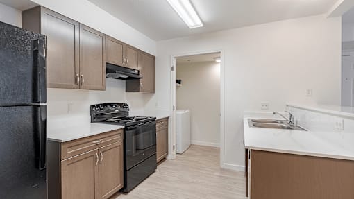 A kitchen with black appliances and brown cabinets at Falls Creek Apartments in Couer d'Alene, Idaho, 83815