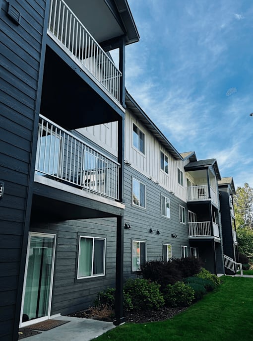 Apartment building with balconies and greenery in front at Falls Creek Apartments in Couer d'Alene, 83815