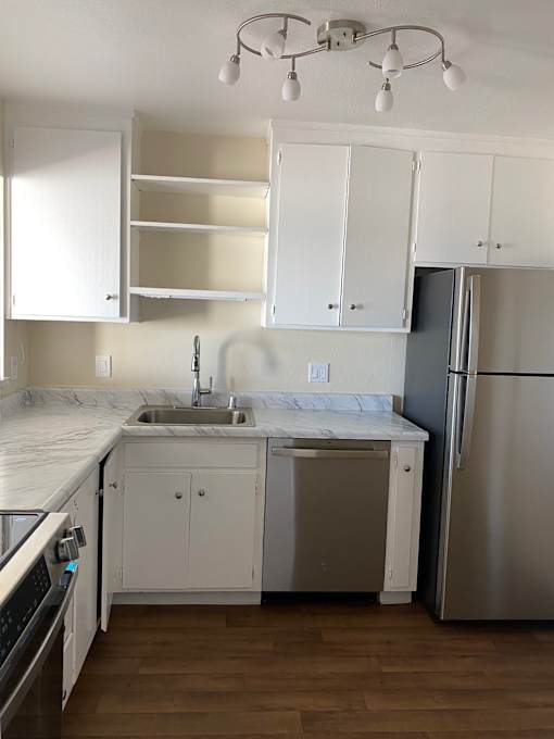 A kitchen with white cabinets and a wooden wall.at Via Casitas, California