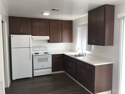 a kitchen with dark wood cabinets and white appliances at MEADOWS HOLLY, VACAVILLE