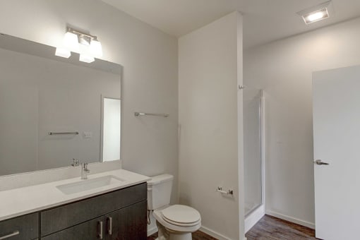 Apartments for Rent in Olympia- Briggs Village- Standing Shower, Wood-Style Floors, Black Cabinets, and Large Mirror
