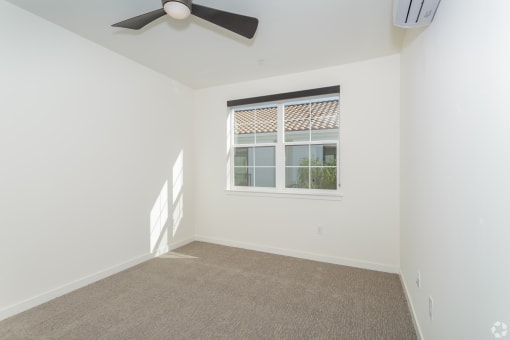 a bedroom with a ceiling fan and a window at THE ANGELINO, Sacramento, 95819