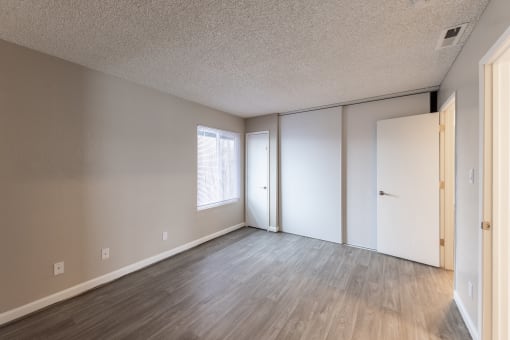 a bedroom with hardwood flooring and two closets