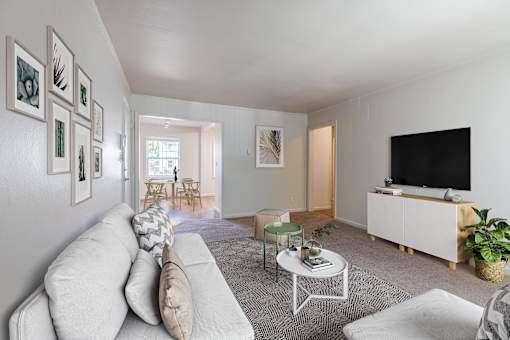 A living room with a white couch, a coffee table, and a television at Lake Washington Apartments, Washington 98118