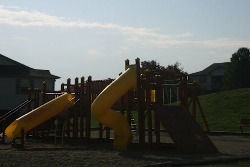 A yellow slide in a playground with a wooden structure.