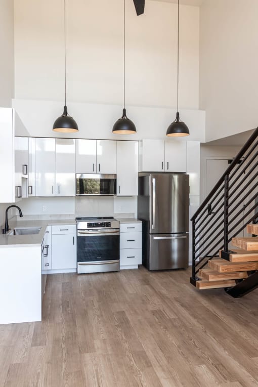 a modern kitchen with white cabinets and stainless steel appliances and stairs at Luella, California