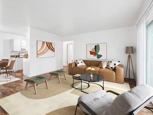 A living room with a brown couch, a grey armchair, and a green ottoman.