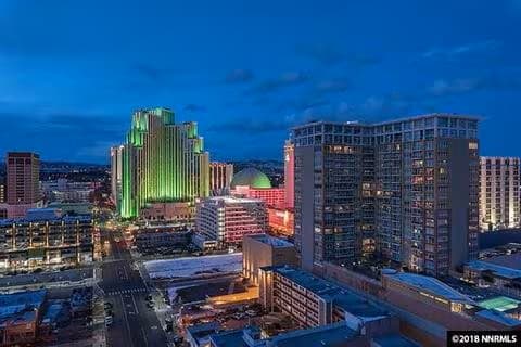 A cityscape at dusk with a prominent green lit building at LOFT 205 Apartments, Reno, Nevada