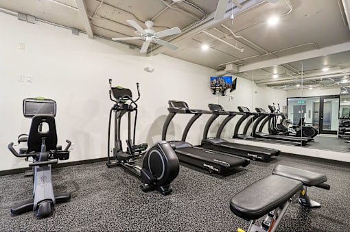 A gym with a variety of equipment including a stationary bike, rowing machine, and treadmills. at LOFT 205 Apartments, Reno, NV, 89501