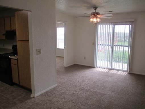 A room with a ceiling fan and sliding glass doors.