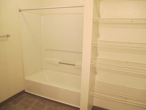 A white walk-in closet with shelves and a bench.