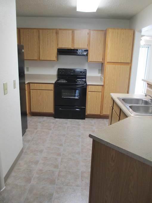 A kitchen with a black stove and wooden cabinets.