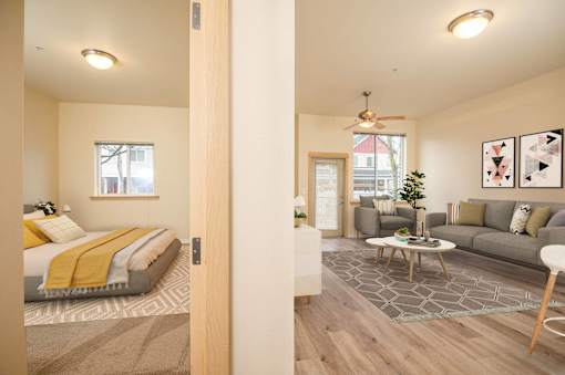 A bedroom with a bed, a couch, a coffee table, and a ceiling fan. at Fairview Village Apartments, Fairview, OR