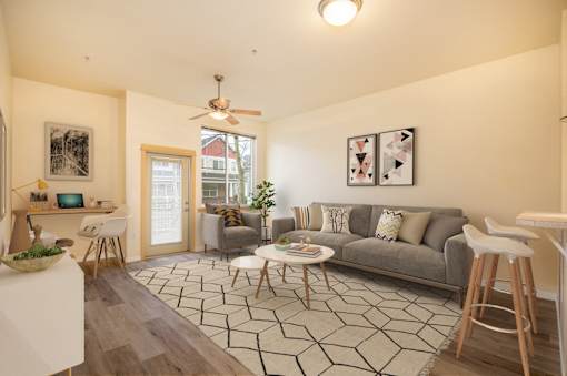 A living room with a grey couch and a black and white rug. at Fairview Village Apartments, Fairview, OR, 97024