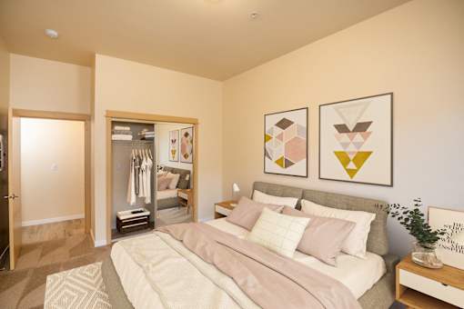 A bedroom with a bed, nightstand, and two framed artworks on the wall. at Fairview Village Apartments, Oregon