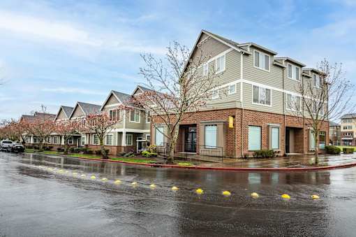 A row of townhouses with a wet street in front. at Fairview Village Homes, Fairview, OR, 97024