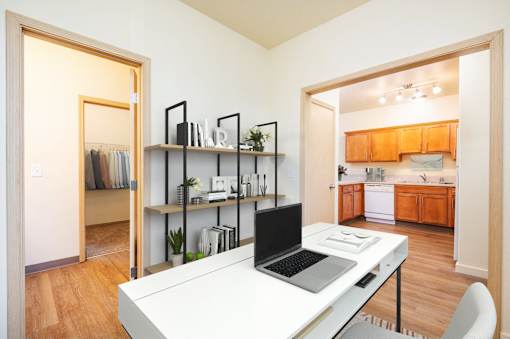 A laptop is on a desk in a room with a kitchen in the background. at Fairview Village Homes, Oregon