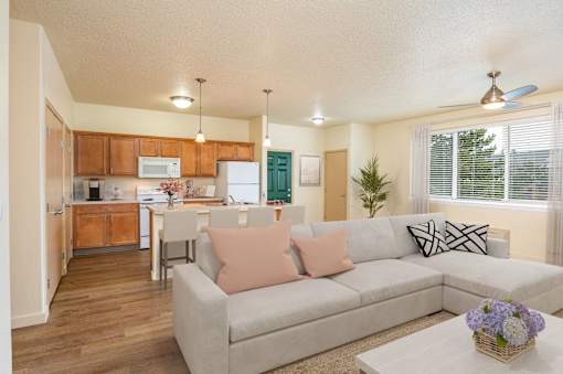A living room with a grey couch and a kitchen area in the background. at Fairview Village Homes, Fairview, OR