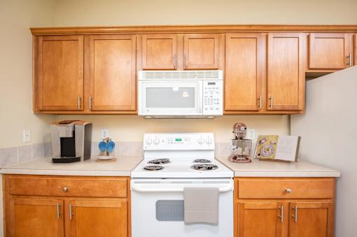 A kitchen with wooden cabinets and a white stove top oven. at Fairview Village Homes, Fairview