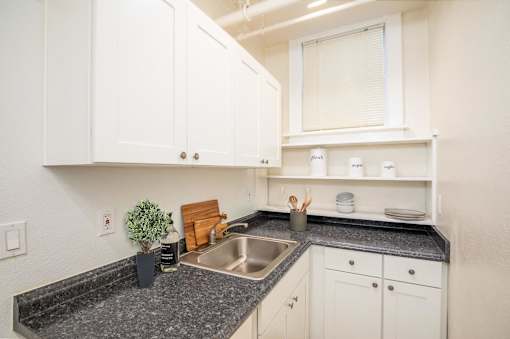 A kitchen with white cabinets and a granite countertop.at Palladian Apartments, Portland Oregon ? 